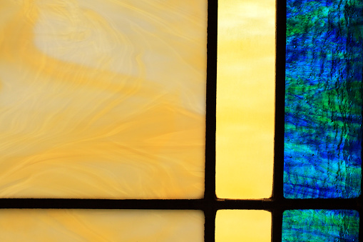 Blues and Yellows in a stained glass window inside of a chapel.