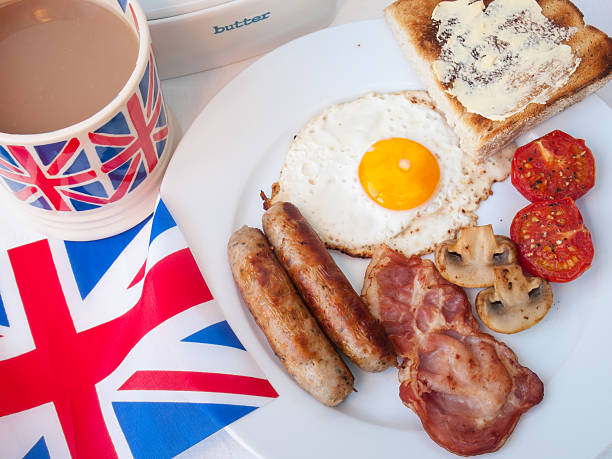 gebratener frühstück mit tasse tee, toast und britische flagge - english breakfast tea stock-fotos und bilder