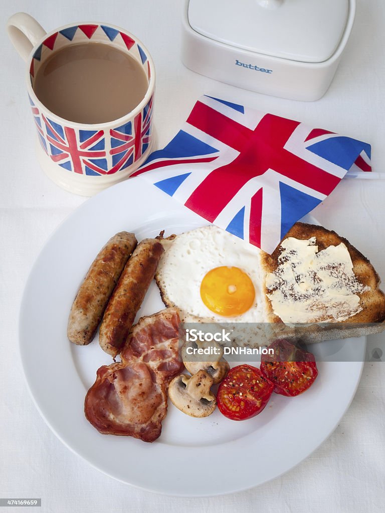 Bacon and eggs with  british flag, tea, butter dish English fried breakfast on a white table top with cup of tea in union jack mug, buttered toast , butter dish and british flag Bacon Stock Photo