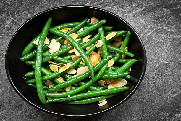 Green Beans with Toasted Almonds in Black Bowl Green beans with toasted almonds, in black bowl over dark slate.  Overhead view. side dish stock pictures, royalty-free photos & images