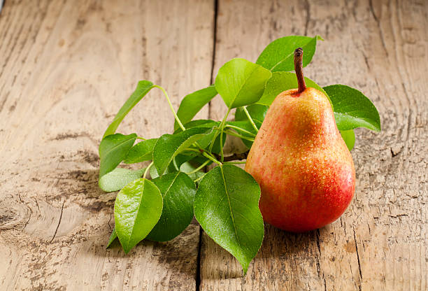 istock Fresh pink pear with drops of water on wooden table 474174664
