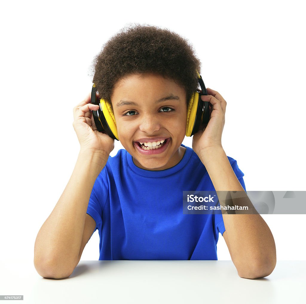 African American school boy listening music with headset Cheerful African American school boy, teenager smiling and  listening music with colorful headset and outfit, education, school and technology concept. Isolated, over white background, with copy space. Boys Stock Photo