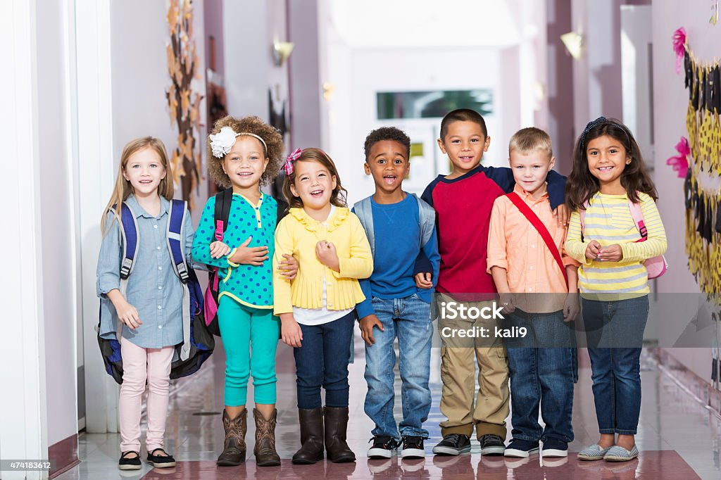 Multiracial group of children in preschool hallway A multi-ethnic group of seven children standing in a row in a school hallway, laughing and smiling at the camera.  The little boys and girls are kindergarten or preschool age, 4 to 6 years. Child Stock Photo
