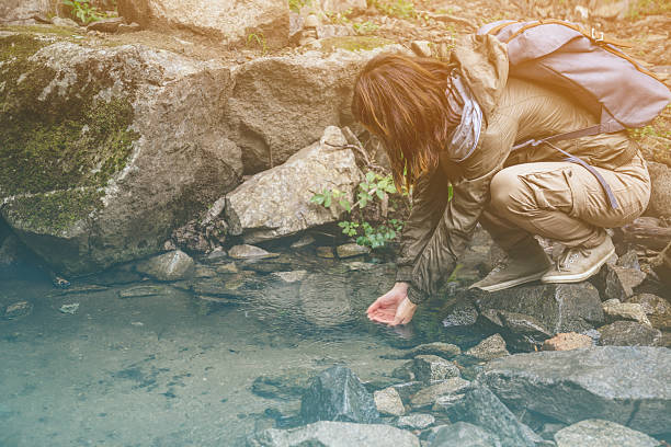 istock Hiker woman drinking a water from creek 474185010