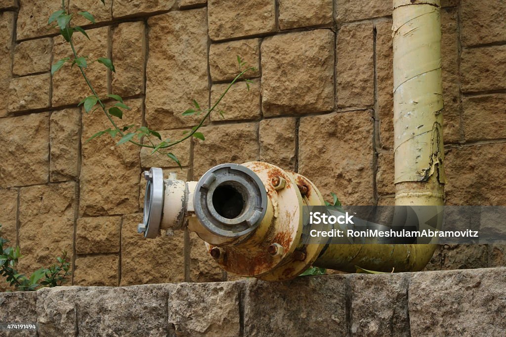 Fire hydrant - dual Headed fire stand pipe - fire protection. Double headed fire hydrant, fire pipe - fire valve for fire fighting coming out of a block wall. Side view. 2015 Stock Photo