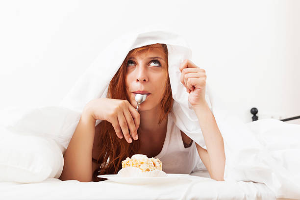 istock Red-haired girl eating biscuit in  bed 474192857