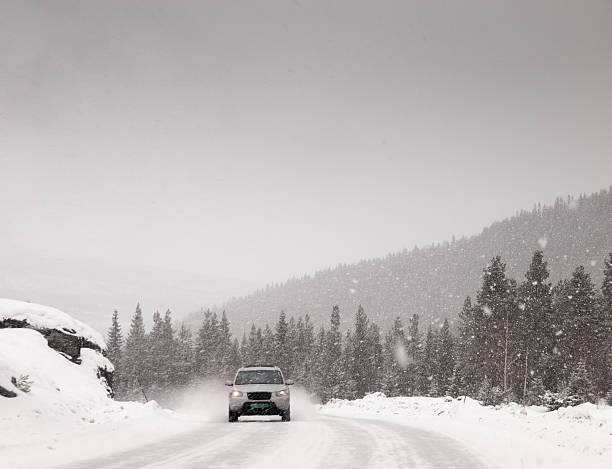 four wheel drive vehicle driving down a snow covered road during a heavy snow storm in the winter.