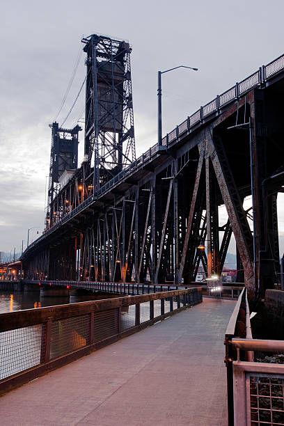 Truss lift transportation bridge with towers walkway through evening river