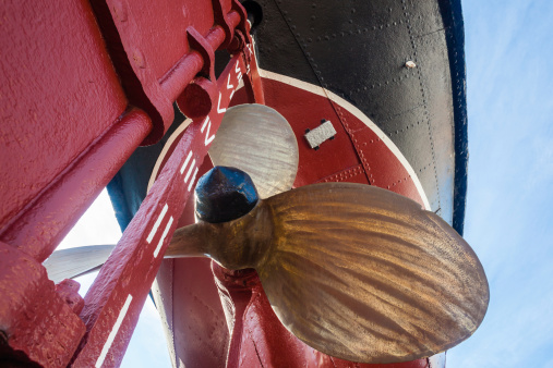 Brass Propellor metal rivet coloured hull of retired steam tug vessel on dry-dock museum
