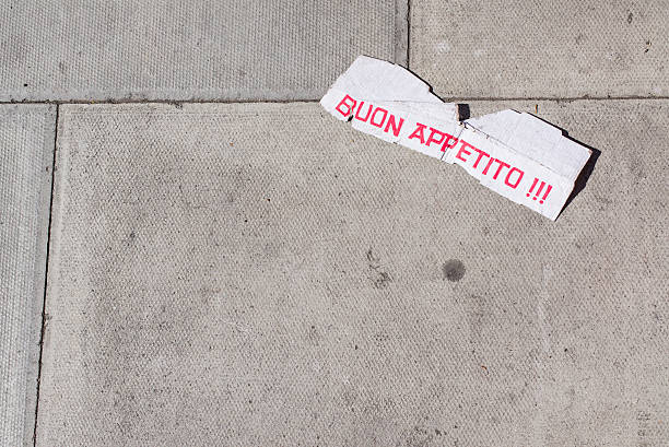White cardboard lying on pavement with Italian words 