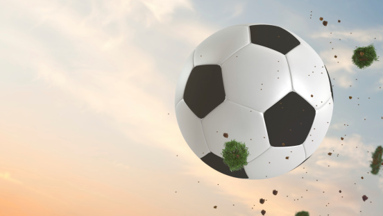 Soccer ball flying through the air after a swing followed by chunks of dirt and earth