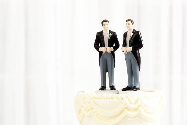 Same Sex Marriage Wedding Cake Figurine Topper Horizontal Subject: Same sex marriage wedding cake with two male groom figurine cake toppers. civil partnership stock pictures, royalty-free photos & images