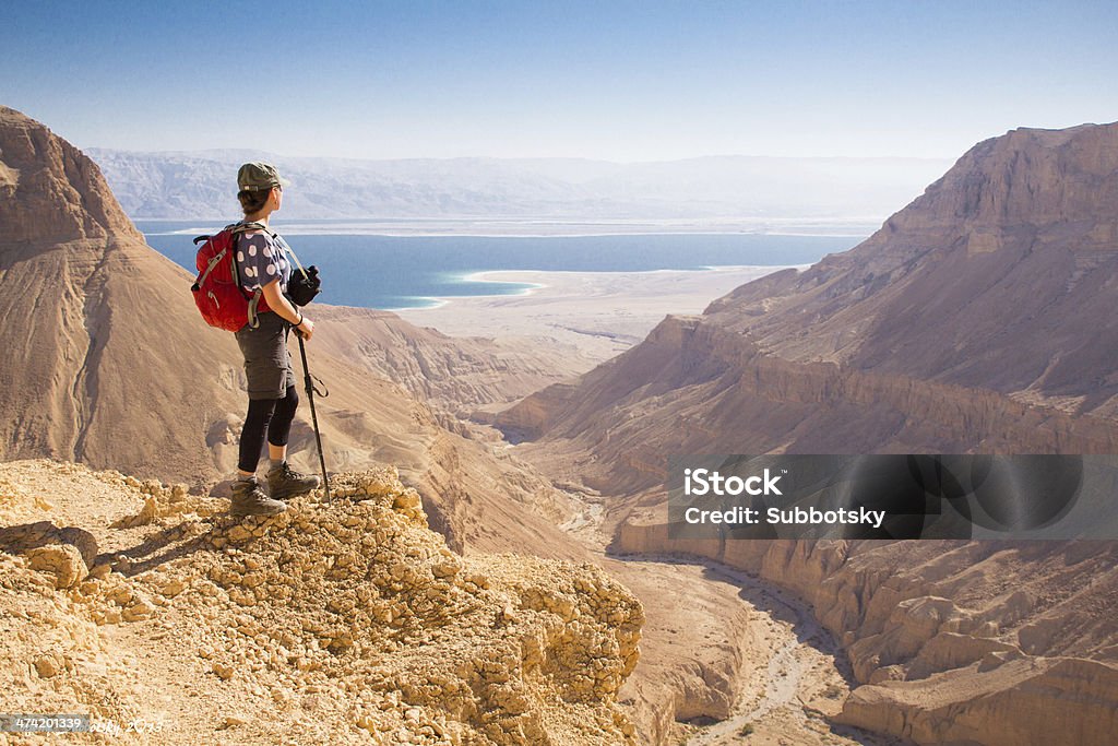 Young female standing on mountain's edge looking towards a sea. Hiking in Dead sea region. Israel Stock Photo
