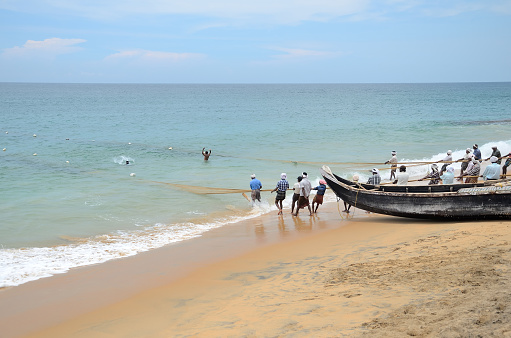 Kovalam, India – April  11, 2015. Traditional fishermen are pulling the seine (fishing net) from the sea in the beach of Kovalam.