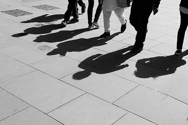 schatten von sechs fuß fußgänger werden auf dem bürgersteig stehen. - rush hour commuter shadow focus on shadow stock-fotos und bilder