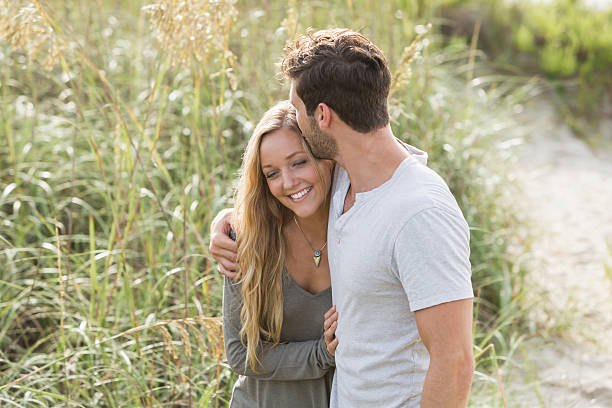 istock Young romantic couple walking on beach sand dunes 474212388