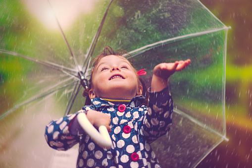 Little girl happily catching drops of rain
