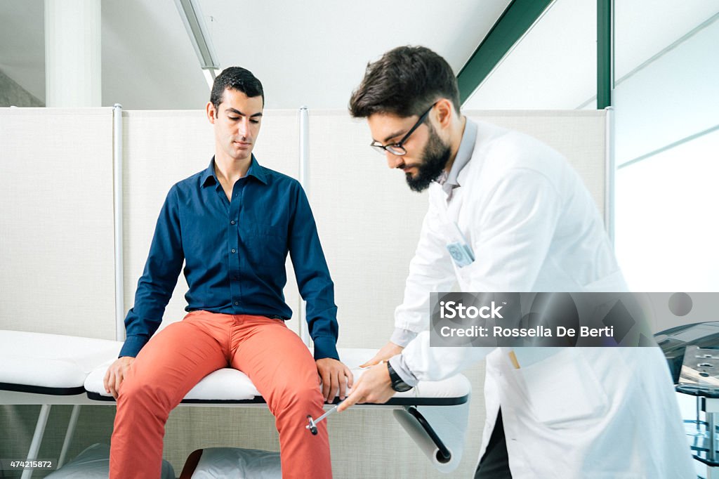 Physical Therapist Examining Patient's Reflexes With Reflex Hammer Physical therapist examining patient's reflexes with reflex hammer Examining Stock Photo