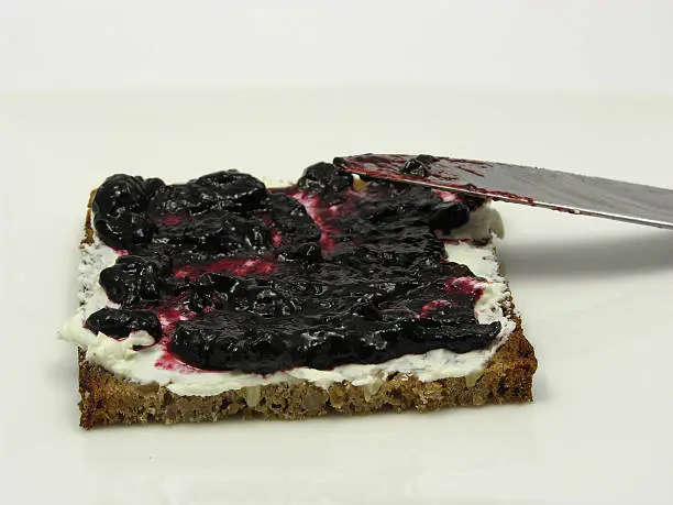 Wholemeal butterbread  with bilberry jam placed on a round plate with knife