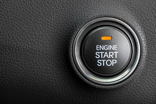 Photograph of start stop push button on dashboard of modern vehicle.