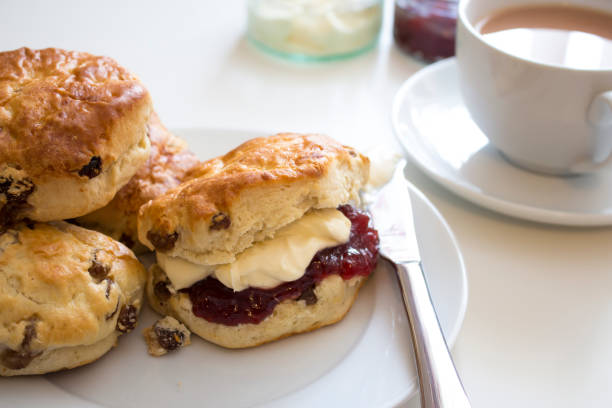 Tea and Scones the British Way Delicious fruit scones, with strawberry jam and clotted cream, served with a cup of tea.  scone photos stock pictures, royalty-free photos & images
