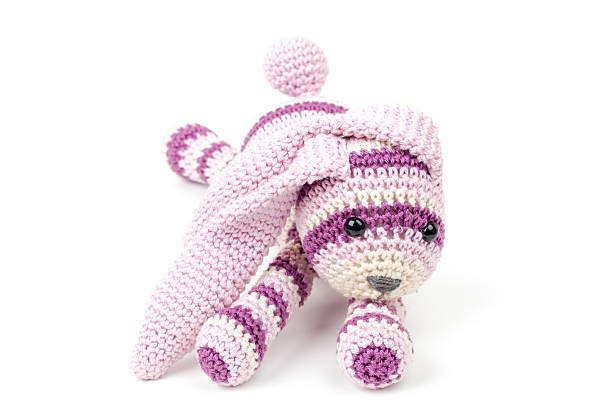 istock Knitted pink rabbit toy lays isolated on white 474233424