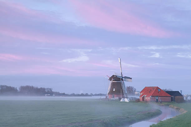 stary wiatrak w sunrise mgła przez river - netherlands windmill farm farmhouse zdjęcia i obrazy z banku zdjęć