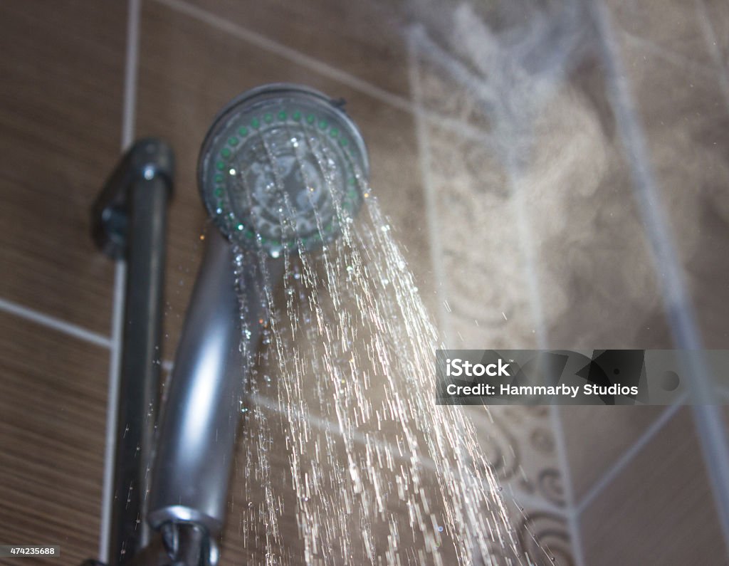Shower head with boiling water and steam in the bathroom Low angle view of flowing shower head in the bathroom. Horizontal composition. Image taken indoors and developed from Raw format. Focus on water. Shower head and other background are blurred. Heat - Temperature Stock Photo