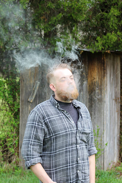 istock Man Surrounded by Vape Cloud in Front of Outhouse 474243824