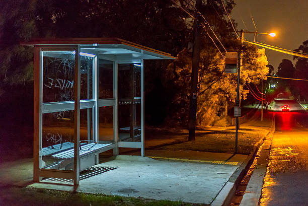 bus shelter at night Empty bus shelter at night. A car is dissappearing down the road. graffiti is scratched into the glass. bus shelter stock pictures, royalty-free photos & images