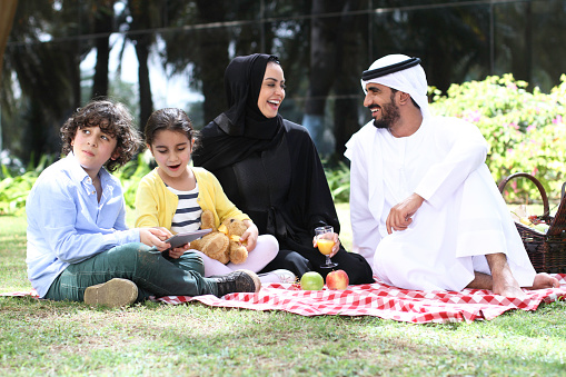 Happy Emirati Family enjoying their picnic time with their two kids in a lovely green area in Dubai, UAE. 