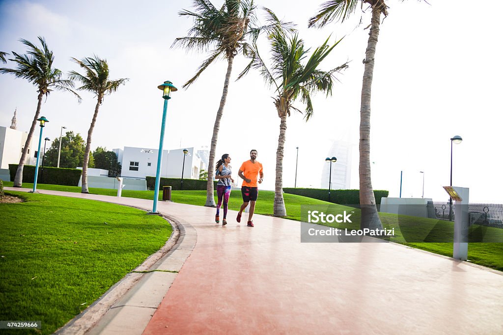 Fitness and exercising in Dubai - Sporty People Young athletic couple exercising in Jumeirah Beach promenade in Dubai, UAE. The two guys starting a fitness run on the sidewalk. The sun shines bright on the background. 2015 Stock Photo