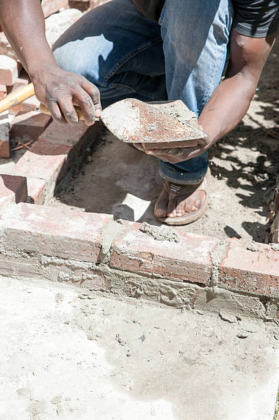 istock African manbuilds garden wall on a sunny day 474260640