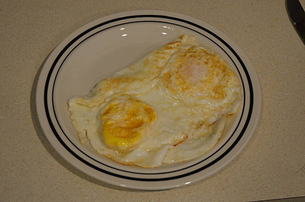 Fried Eggs Two eggs fried in butter on small plate. jtmcdaniel stock pictures, royalty-free photos & images