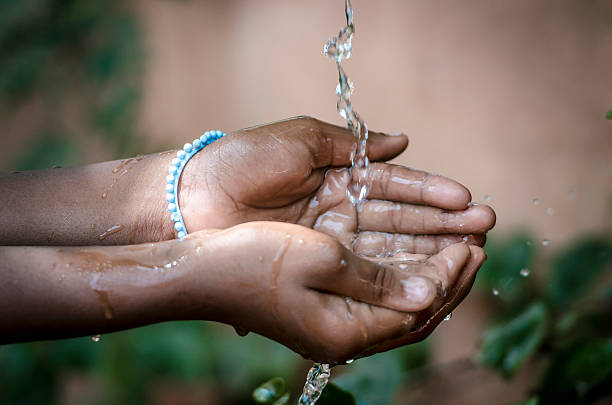 Hands Cupped Under Tap To Collect Water For African Girl stock photo