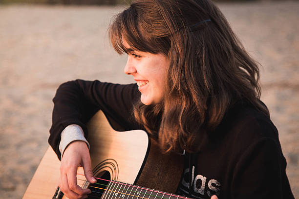 istock young girl playing guitar sitting on the sand 474279738