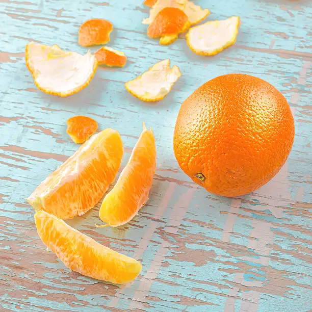 Fresh Ripe Sweet Orange Tropical Fruit, Sliced Sections and Peel on Rustic Grunge Blue Wood Background