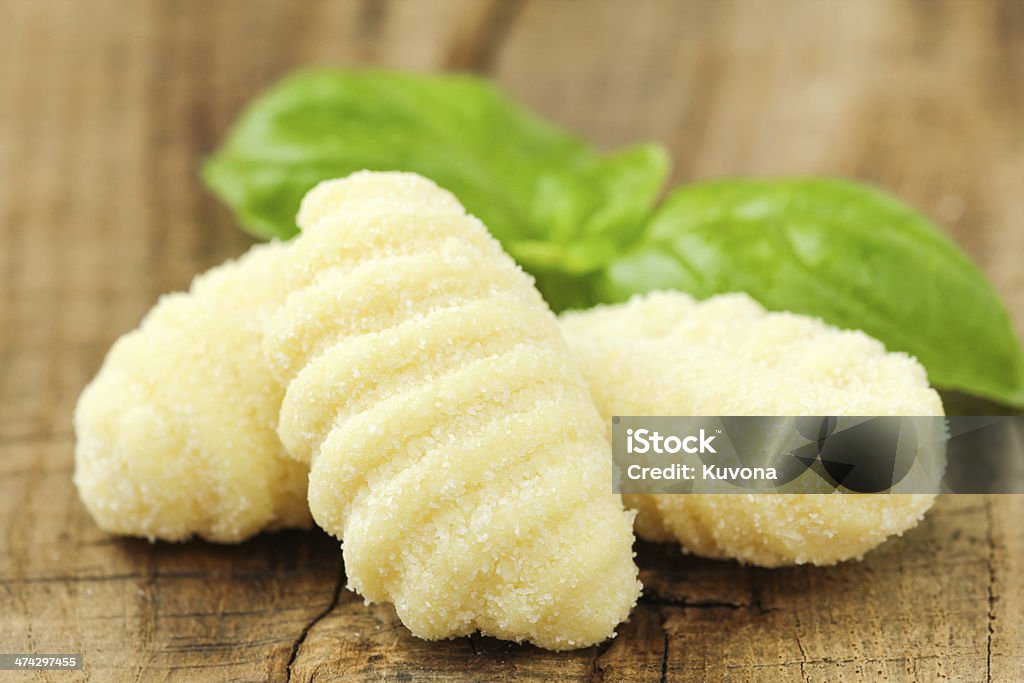 Potato gnocchi Potato gnocchi with a sprig of fresh basil at the background on a rustic wooden table Basil Stock Photo