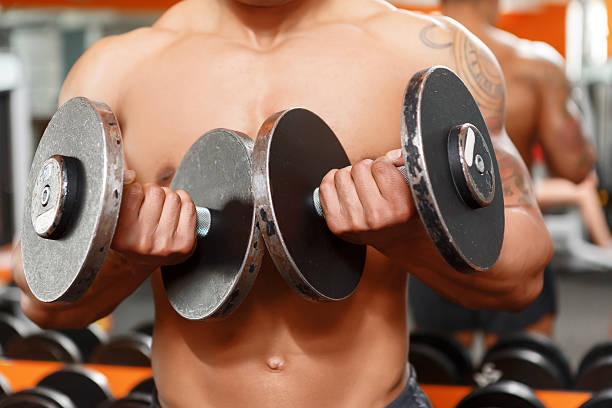 istock Man lifting two dumbbells in gym 474299716
