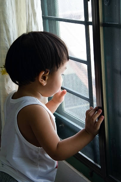 istock boy standing near the window 474301924