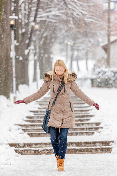 istock Beautiful woman walking on snow while snowing 474312509