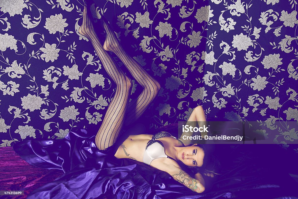 Boudoir A sexy woman in fish net stockings and lingerie.  Bed - Furniture Stock Photo