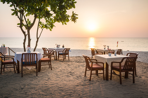 Empty restaurant on the sand beach in sunset
