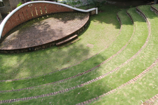 Small amphitheater made with red bricks and seats arranged in a circular manner, covered with green fresh soft grass