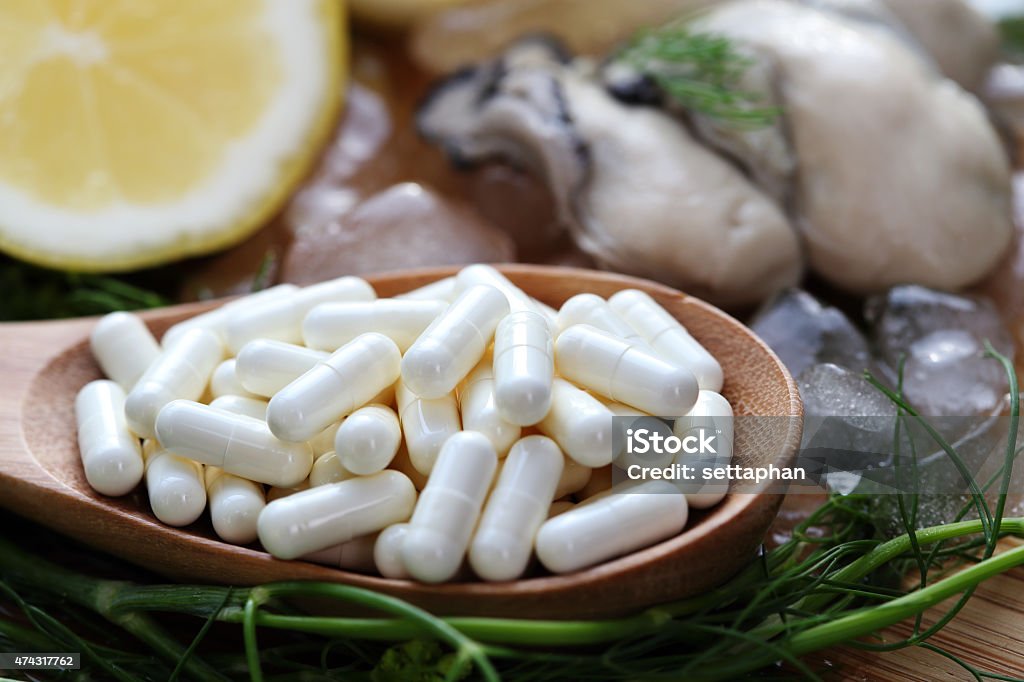 The zinc supplementary white capsule with fresh oyster on block The zinc supplementary white capsule with fresh oyster on block wood Zinc Stock Photo