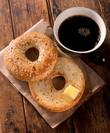 A delicious toasted everything bagel with melted butter and black coffee.