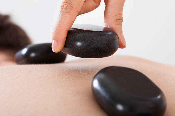 セラピストが温めた石を置く男性の背中にスパ - massaging spa treatment stone massage therapist ストックフォトと画像