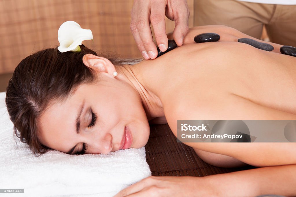 Beautiful young woman getting hot stone therapy Beautiful young woman getting hot stone therapy at spa salon 2015 Stock Photo