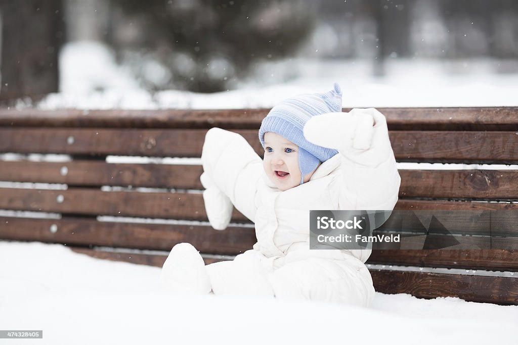 Cute funny baby sitting on bench in park Cute funny baby sitting on a bench in a park on a snowy winter day Baby - Human Age Stock Photo