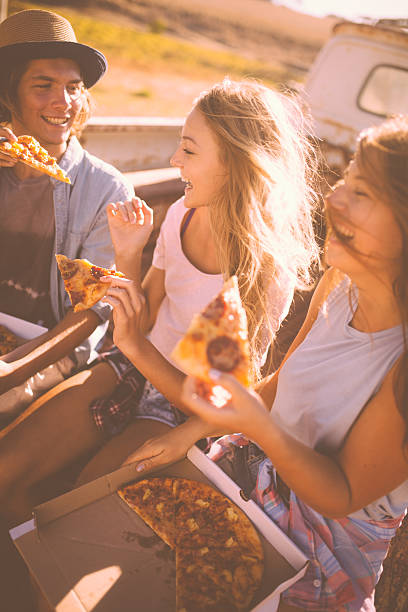 istock Laughing teens sharing pizza outside on a summer day 474331216